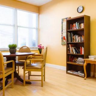 A cozy room interior with a table, chairs, and a bookshelf.
