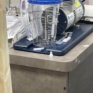 A medical suction device placed on a countertop in a healthcare setting.