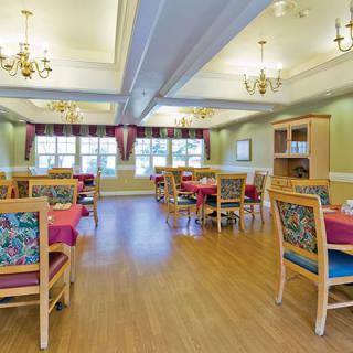 A brightly lit dining room with colorful chairs and neatly arranged tables.