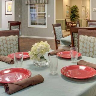 Elegantly set dining table with red plates and flowers.