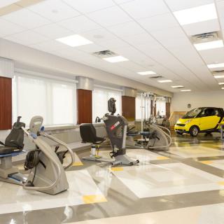 Rehabilitation center with exercise equipment and a small car for therapy purposes.