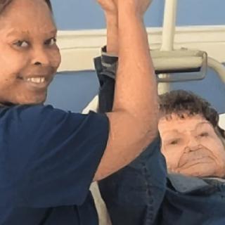 A healthcare worker assists an elderly patient during a physical therapy session.