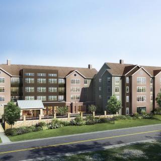 A modern suburban apartment building with a landscaped front yard.