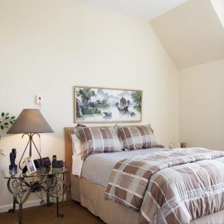A cozy bedroom with plaid bedding, a decorative lamp, and artwork above the bed.