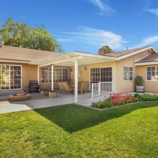 A cozy backyard with a patio, lush lawn, and garden under a sunny sky.