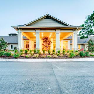 Elegant building entrance illuminated with warm lights and surrounded by landscaped gardens.