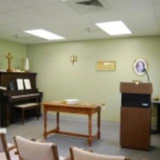 A small chapel with a piano, podium, and rows of chairs.