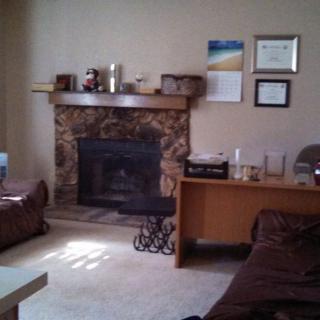 A cozy living room with a stone fireplace and comfortable seating.