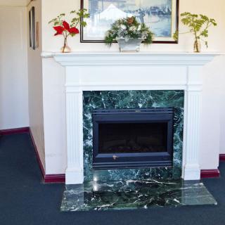 A stylish fireplace with a marble surround, adorned with plants and artwork.