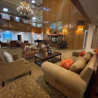 A luxurious hotel lobby with elegant seating, a grand chandelier, and wooden wall paneling.