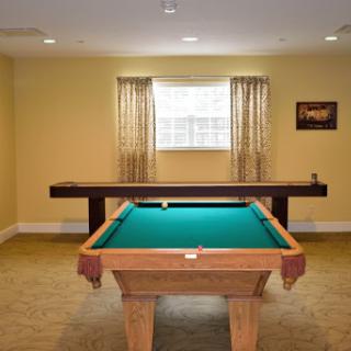 A spacious game room featuring a pool table and inviting yellow walls.