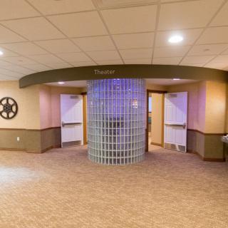 The entrance to a theater lobby featuring movie reel decorations and modern lighting.