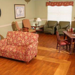A cozy living room with a patterned sofa, chairs, and wooden flooring.