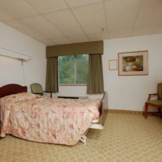 A hospital room with a single bed, window, and seating area.