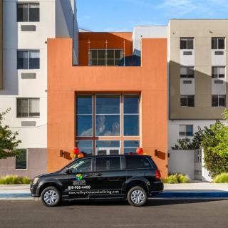 A black SUV parked in front of a modern, multicolored building.
