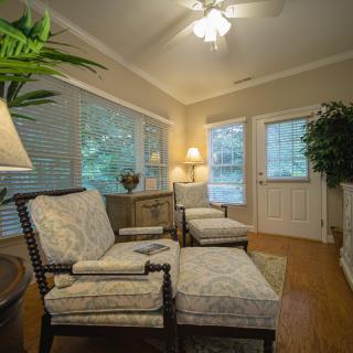 A cozy living room with comfortable armchairs, soft lighting, and large windows.