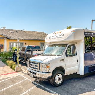 A shuttle bus parked in a lot outside a building on a sunny day.