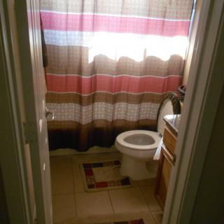 A small bathroom with a toilet, shower curtain, and tiled floor.