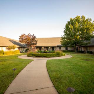 A serene courtyard with a winding pathway surrounded by green lawns and trees.