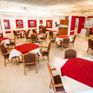 An elegantly decorated restaurant dining area with tables covered in red tablecloths and art adorning the walls.