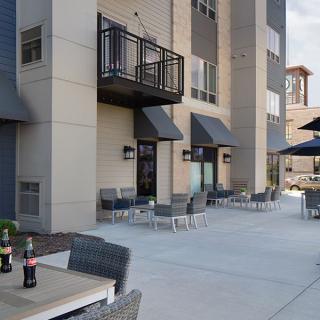 Outdoor patio area with seating and balconies at a residential building.