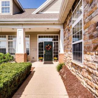 A welcoming entrance to a suburban house with a brick facade and a wreath on the front door.