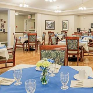 A cozy dining room setup with neatly arranged tables and chairs, featuring elegant table settings and a small bouquet of flowers on each table.