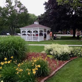 A serene garden scene featuring a white gazebo surrounded by vibrant flowers.