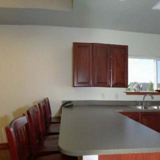 A kitchen with a counter, chairs, and cabinets.