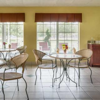 A cozy cafe setting with wicker chairs and round tables by large windows.