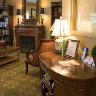 A cozy living room with warm lighting, featuring a fireplace, elegant furniture, and a well-stocked bookshelf.