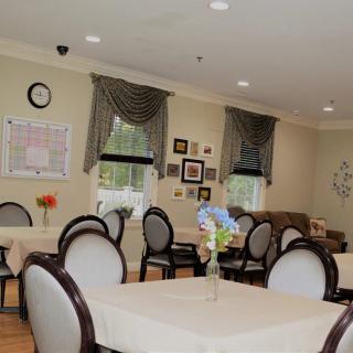 A cozy dining room with neatly arranged tables and chairs, adorned with floral centerpieces and decorated walls.