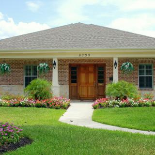 A well-maintained brick house with a manicured lawn and colorful garden.