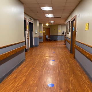 A view of a hospital hallway featuring wooden floors and warm lighting.