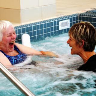 Two women enjoying a fun moment together in a spa pool.