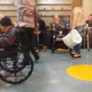 A bustling indoor area with people seated and in motion, including a person in a wheelchair.