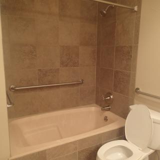 A bathroom featuring a bathtub with tiled walls and a toilet.