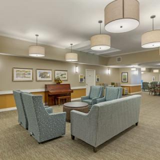 A cozy lounge area with sofas, a piano, and elegant lighting.