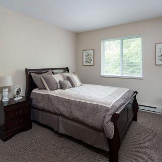 A cozy bedroom with a neatly made bed and a window letting in natural light.