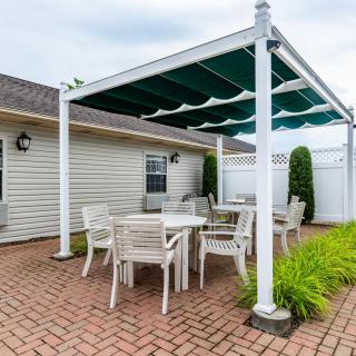 Outdoor patio with a pergola and dining furniture set on brick flooring.