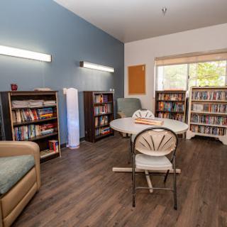 A cozy reading room with bookshelves, a comfortable seating area, and plenty of natural light.