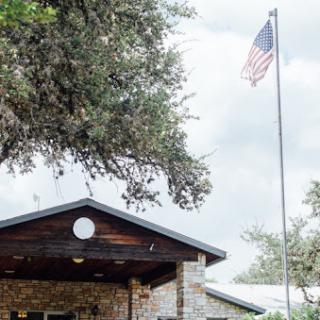 A charming building with an American flag flying above, surrounded by greenery.
