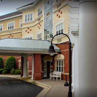 The entrance of a multi-story hotel building with a covered driveway and decorative pillars.