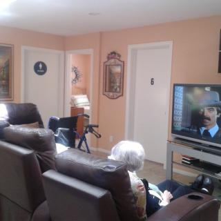 An elderly person sits in a living room watching television.