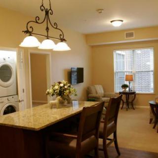 An open-plan kitchen and living area with a dining counter, elegant lighting, and a washer-dryer unit.