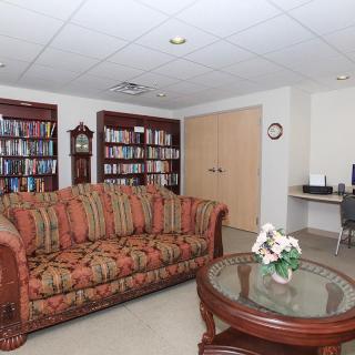 A cozy living room with a patterned sofa, bookshelf, and coffee table.