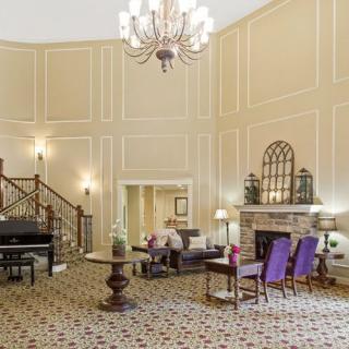 An elegant lobby with a grand chandelier, comfortable seating, and a decorative staircase.