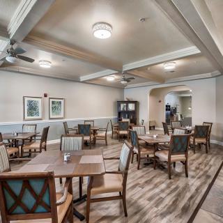 A well-lit dining room with multiple tables and chairs arranged neatly.