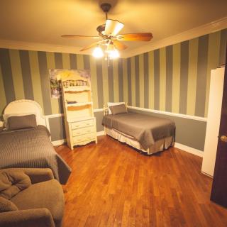 A cozy bedroom featuring two beds, striped wallpaper, and a ceiling fan.