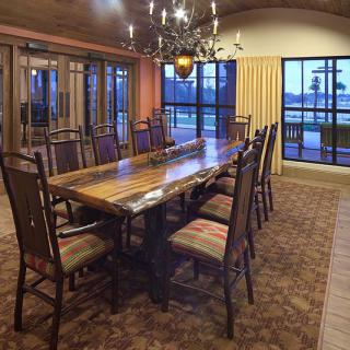 A spacious dining room featuring a large wooden table surrounded by chairs, illuminated by a chandelier.